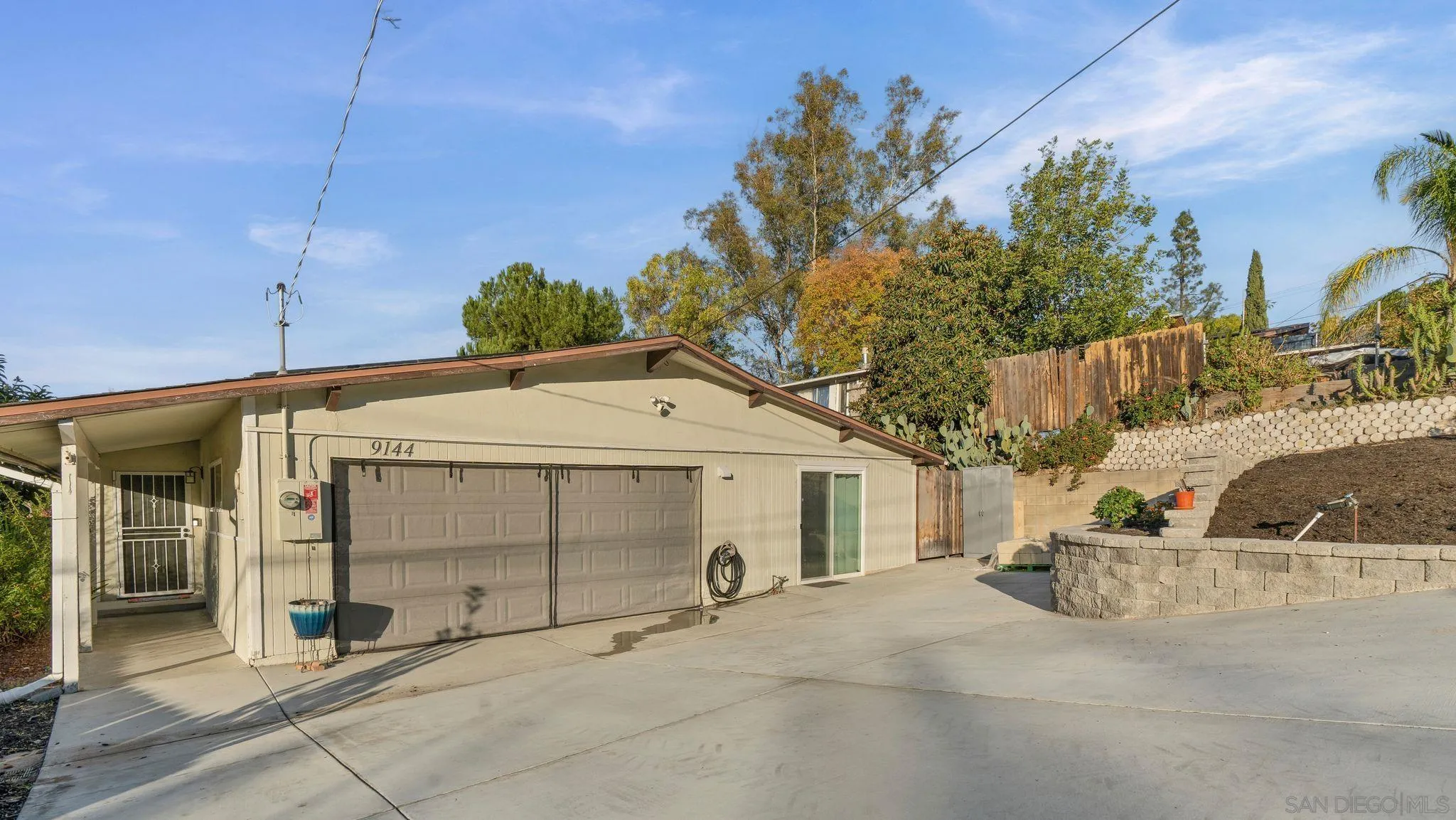 9144 Fanita Rancho Road Santee, CA 92071 - Photo 3 of 28 a view of a white house with a large tree and wooden fence