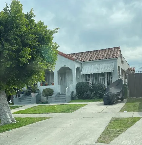 a front view of a house with a yard and potted plants