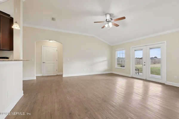 a view of an empty room with a window and wooden floor