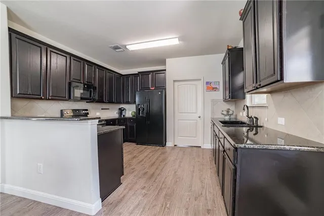 a kitchen with granite countertop wooden floors appliances and cabinets