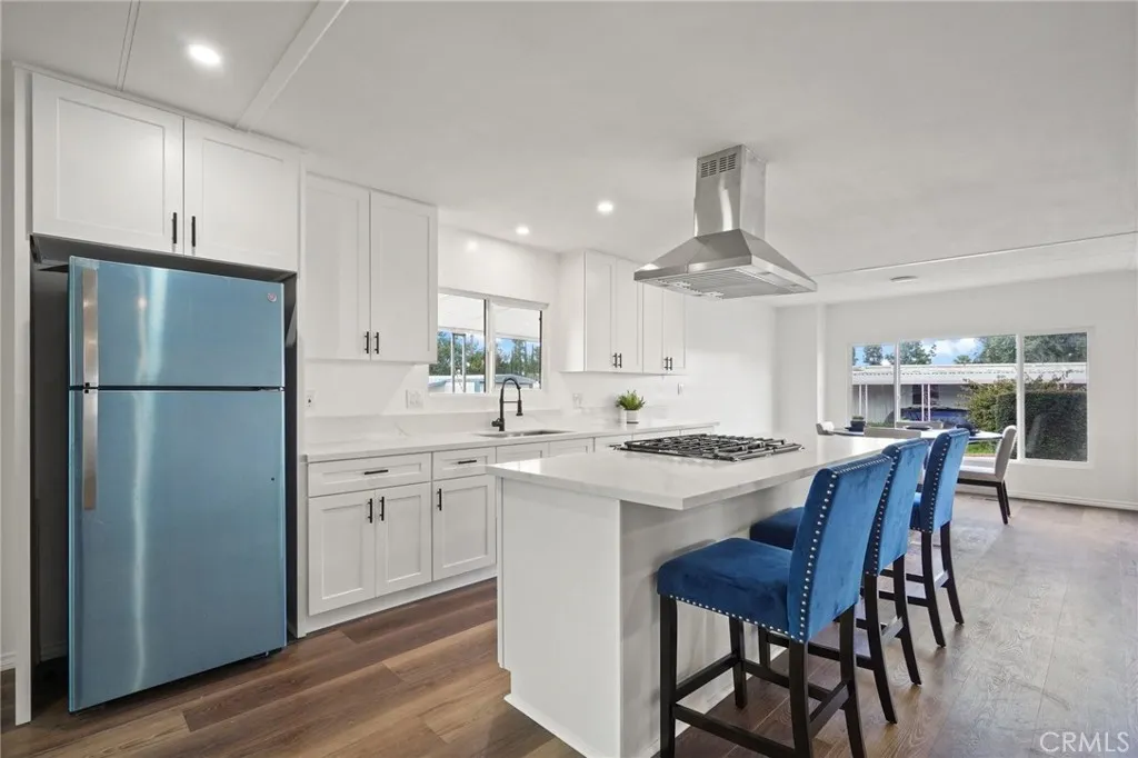 3033 E Valley, Unit 89 West Covina, CA 91792 - Photo 16 of 55 a kitchen with stainless steel appliances granite countertop a dining table chairs refrigerator sink and cabinets