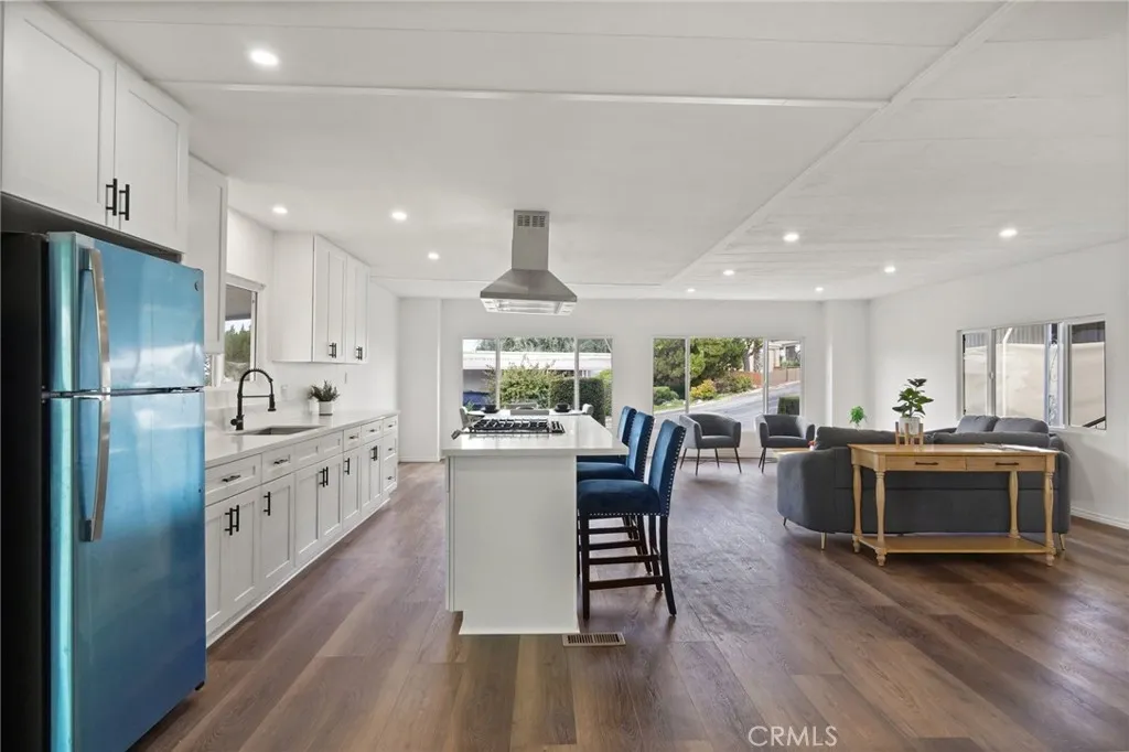 3033 E Valley, Unit 89 West Covina, CA 91792 - Photo 19 of 55 a kitchen with stainless steel appliances kitchen island granite countertop a refrigerator a stove a dining table and chairs with wooden floor