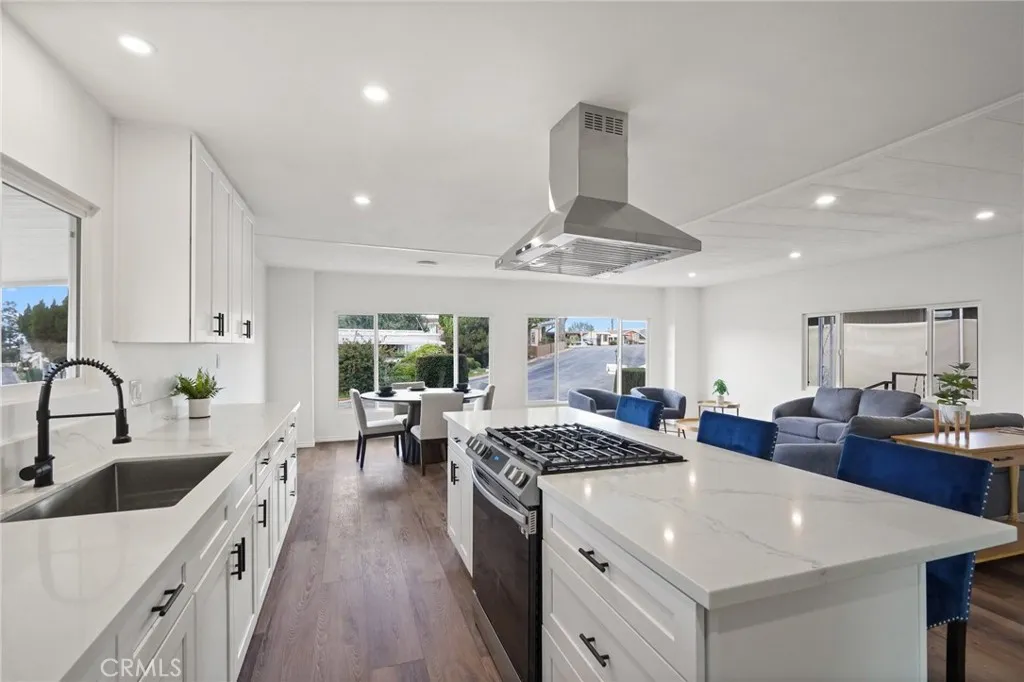 3033 E Valley, Unit 89 West Covina, CA 91792 - Photo 2 of 55 a kitchen with stainless steel appliances a sink dishwasher a stove a dining table and chairs with wooden floor