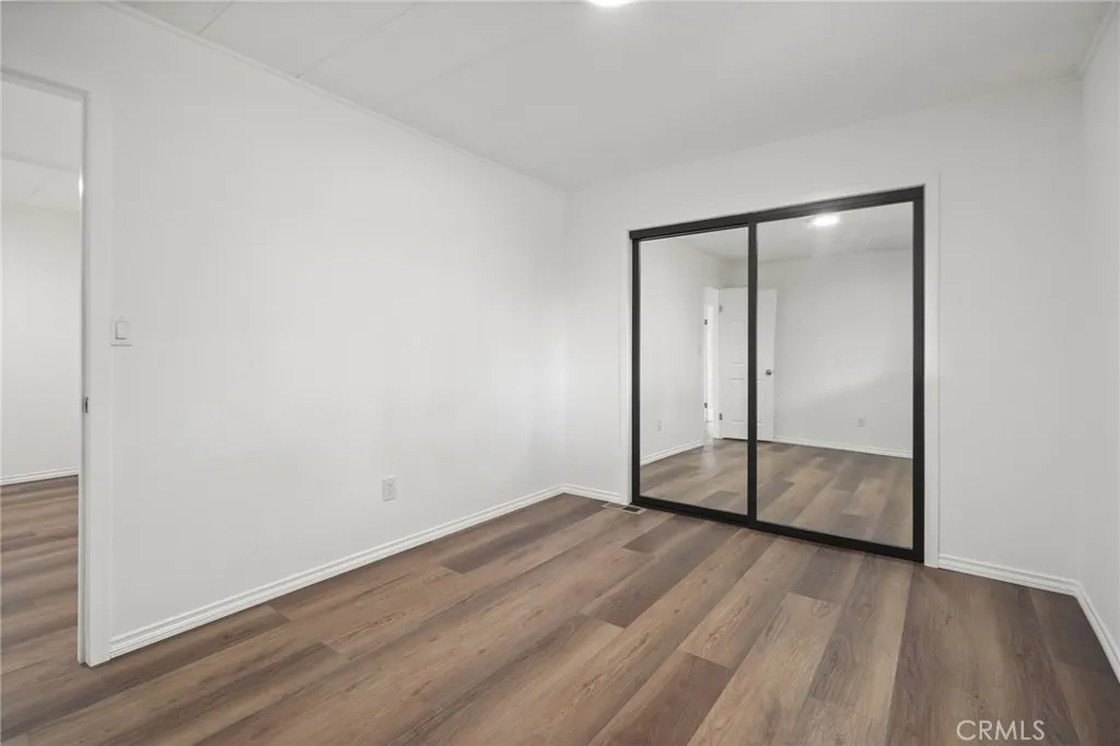 3033 E Valley, Unit 89 West Covina, CA 91792 - Photo 33 of 55 an empty room with wooden floor and mirror