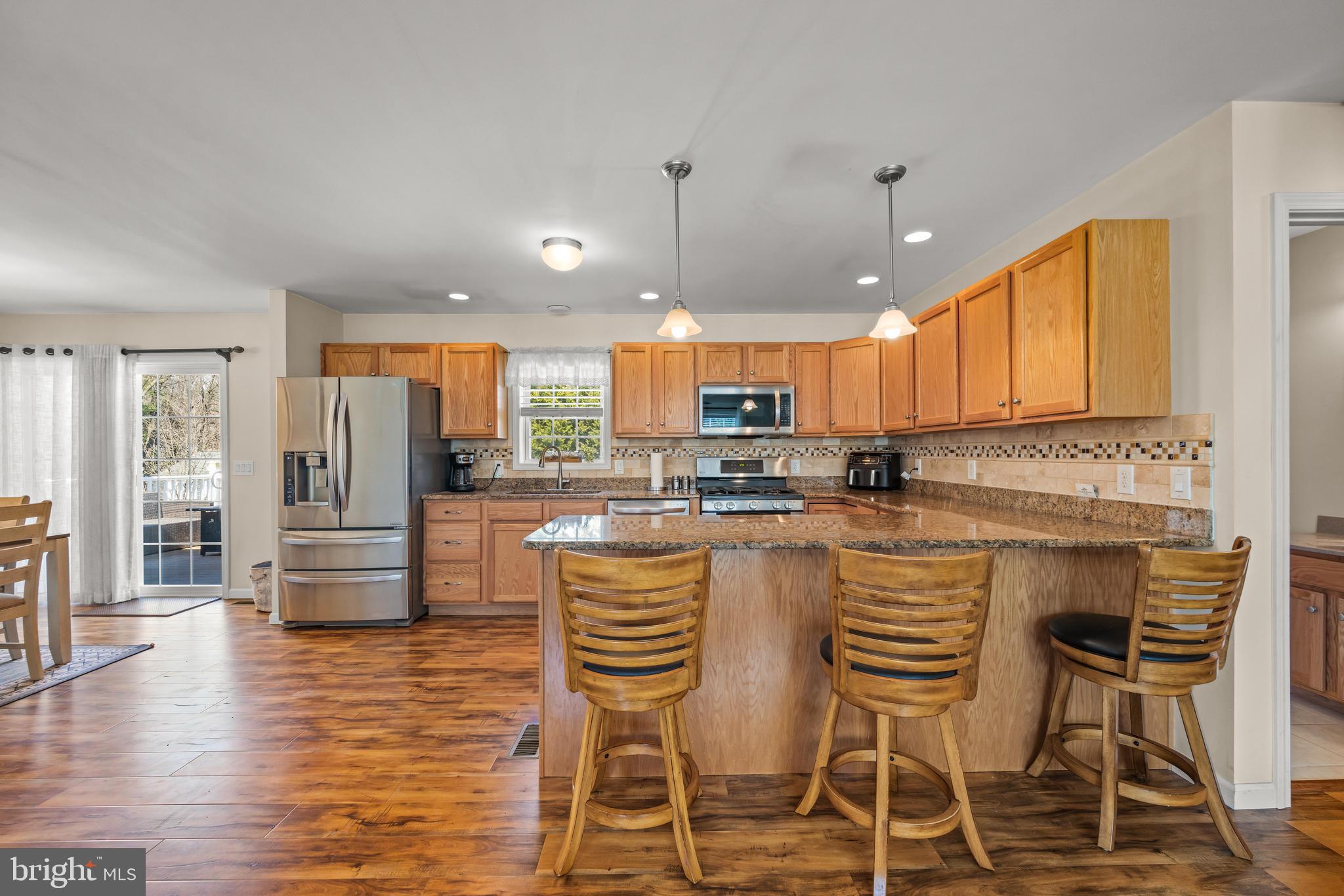 141 Pine Trail Delta, PA 17314 - Photo 8 of 44 a kitchen with stainless steel appliances granite countertop a stove top oven a refrigerator a sink and a dining table with wooden floor