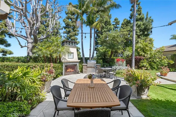 a view of a patio with table and chairs potted plants and a large tree
