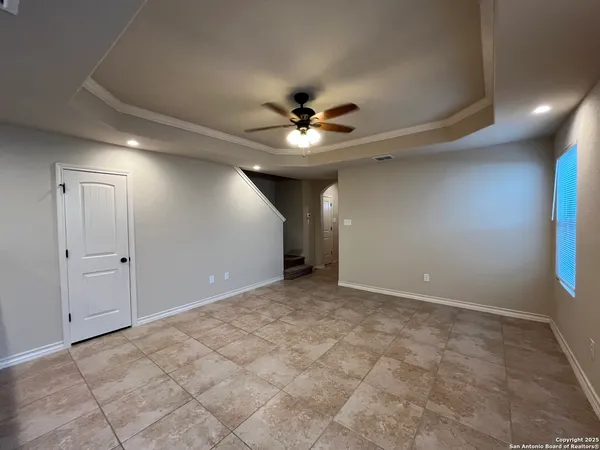 a view of an empty room and chandelier fan