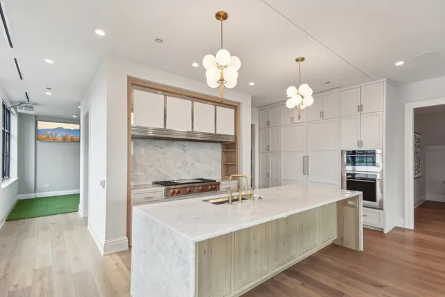 a kitchen with kitchen island granite countertop a stove a sink a refrigerator and a dining table with wooden floor