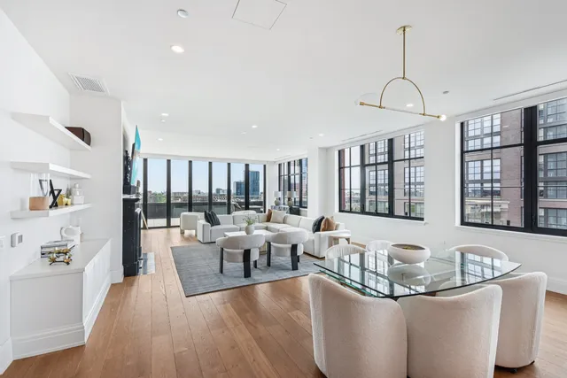 a living room with lots of furniture wooden floor and floor to ceiling window