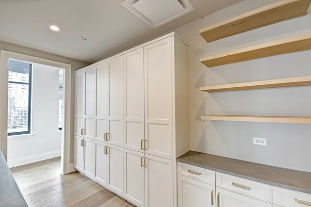 a hallway with white cabinets and wooden floor