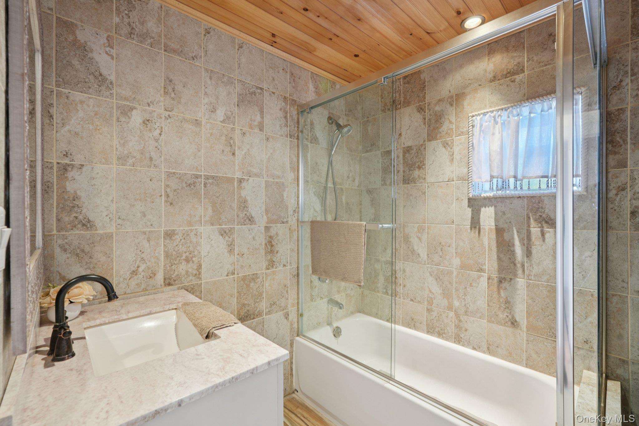 17 Pine Hill Road Highland Mills, NY 10930 - Photo 12 of 35 Bathroom with vanity, shower / bath combination with glass door, tile walls, and wood ceiling