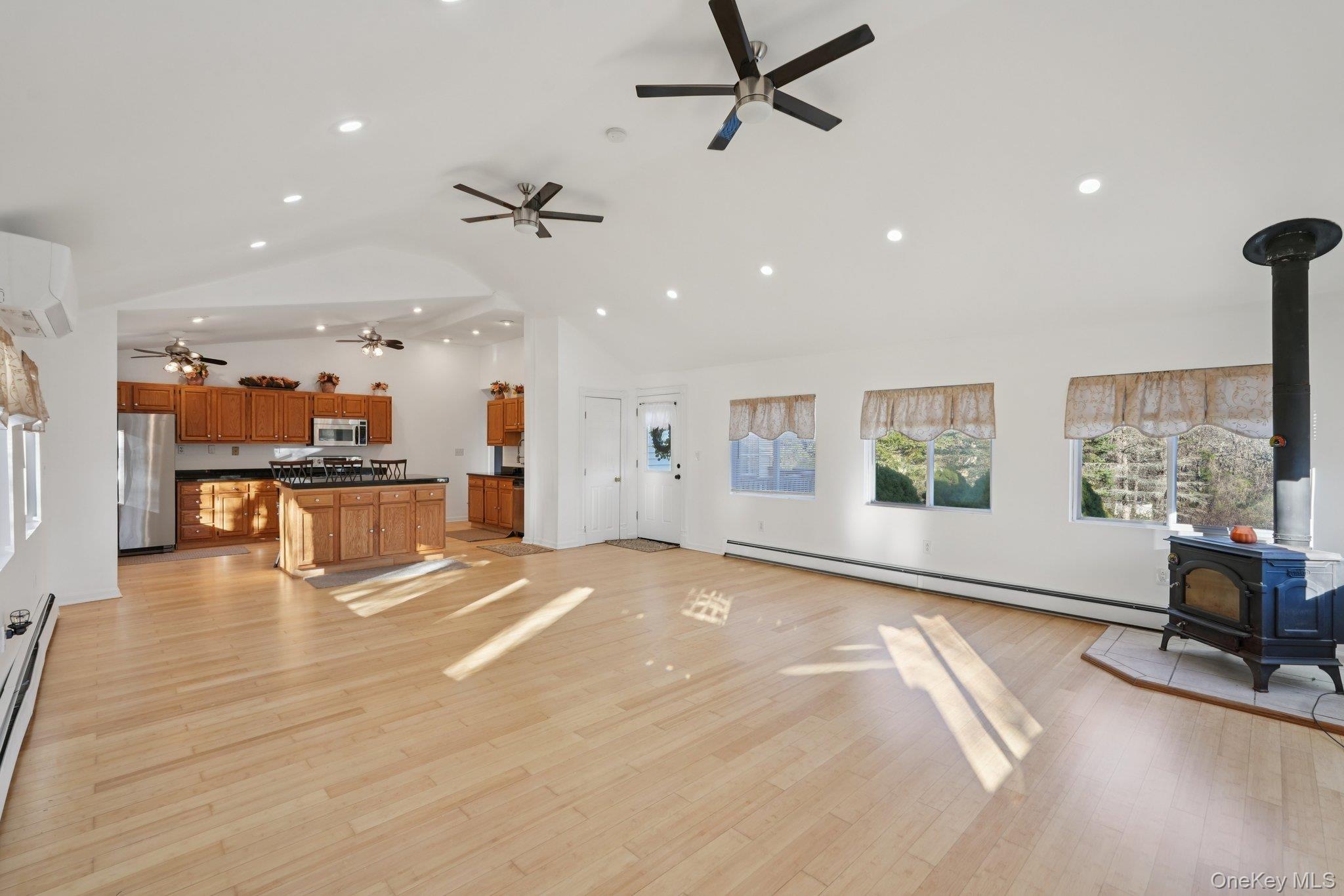 17 Pine Hill Road Highland Mills, NY 10930 - Photo 10 of 35 Dinning room and living room featuring a wood stove, baseboard heating, light wood finished floors, recessed lighting, and a baseboard heating unit