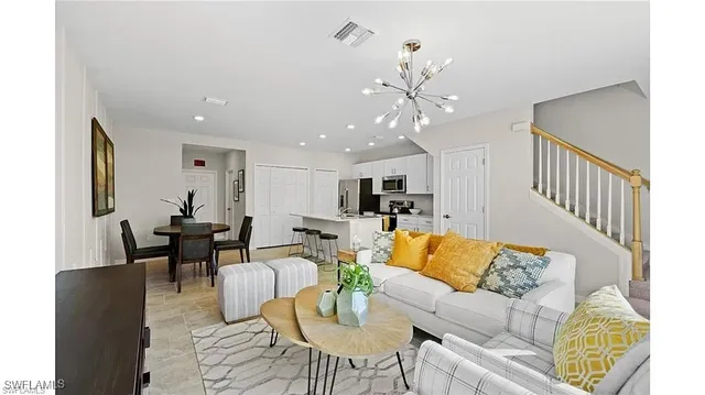 a living room with furniture kitchen view and a chandelier