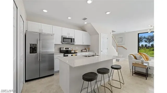 a kitchen with stainless steel appliances a refrigerator a stove a sink and chairs