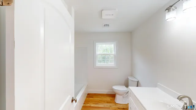 a bathroom with a toilet a sink and a window