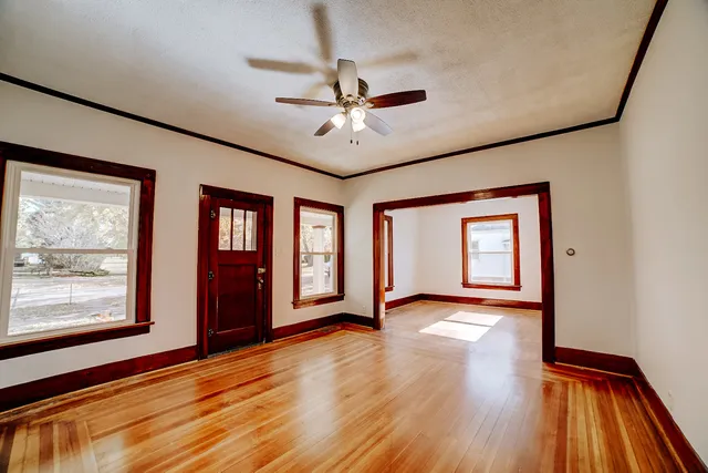 a view of an empty room with window and wooden floor