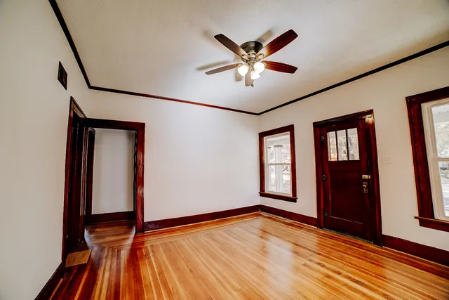a view of empty room with wooden floor and fan