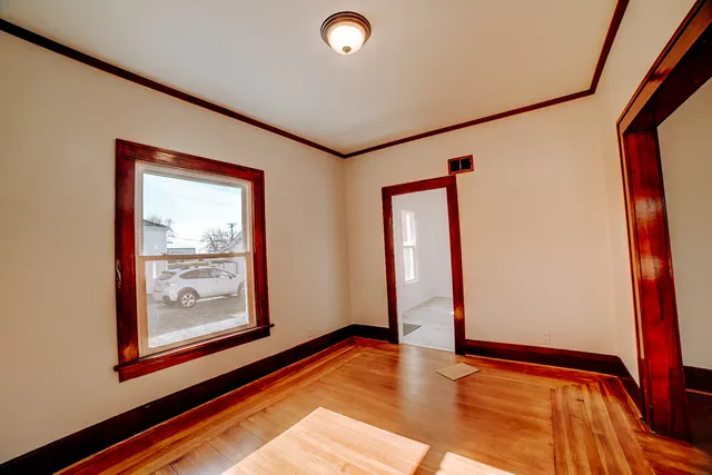 a view of an empty room with window and wooden floor