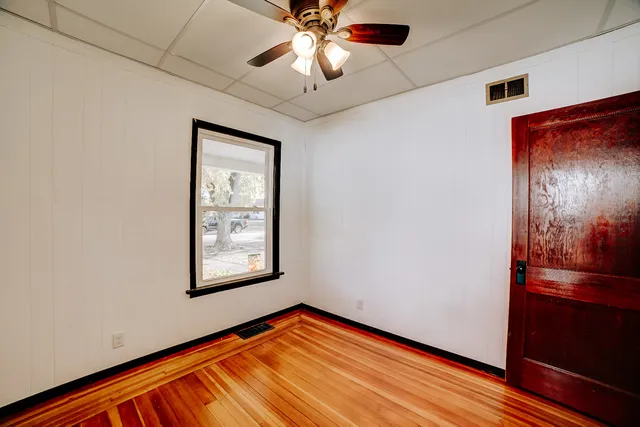 a view of an empty room with window and wooden floor