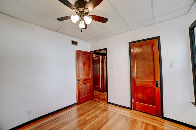 an empty room with wooden floor chandelier fan and closet