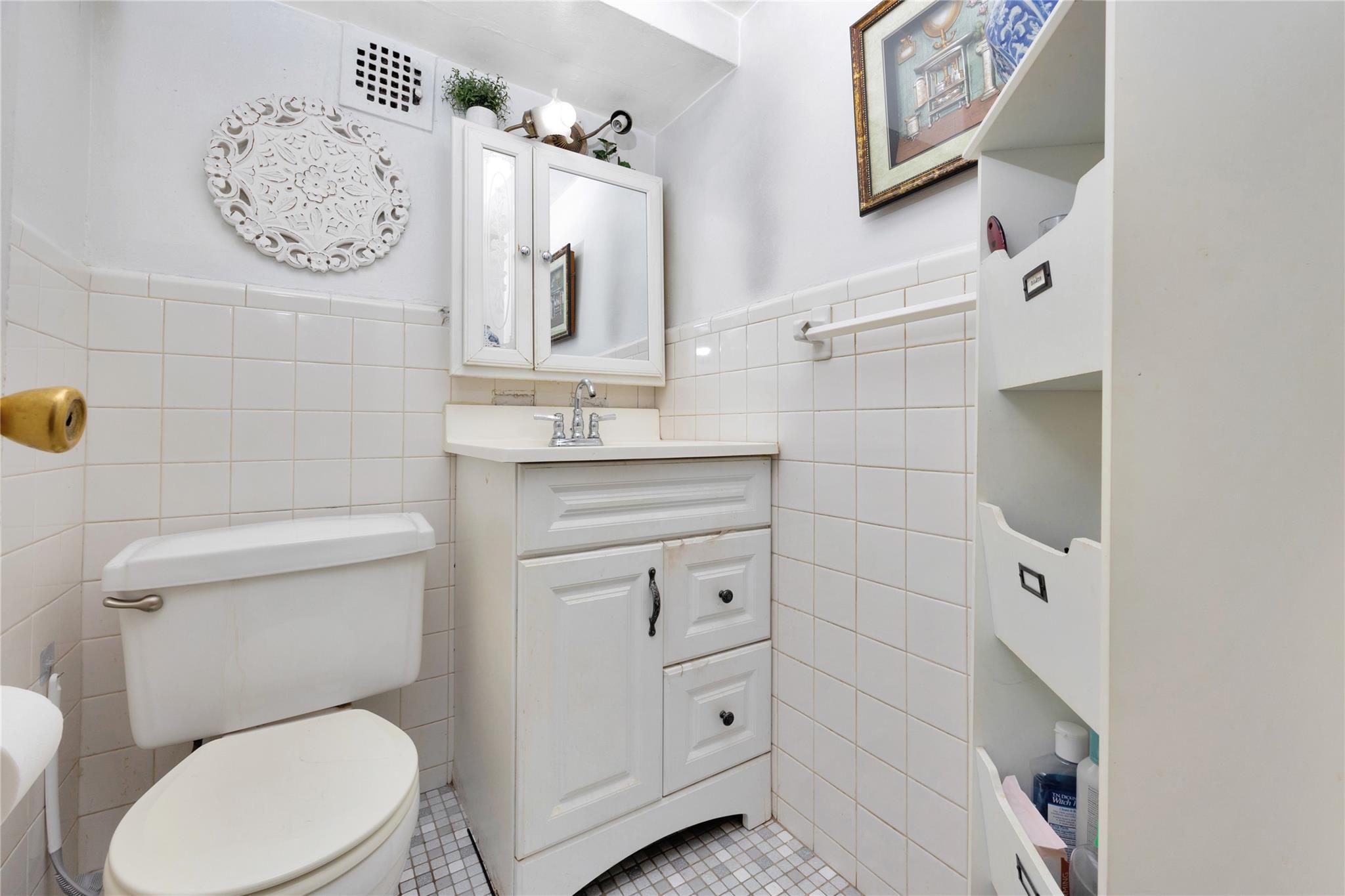 99-40 63rd Road, Unit 9Z Queens, NY 11374 - Photo 14 of 21 Bathroom with tile walls, tile patterned floors, a wainscoted wall, toilet, and vanity