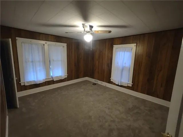 an empty room with ceiling fan and window