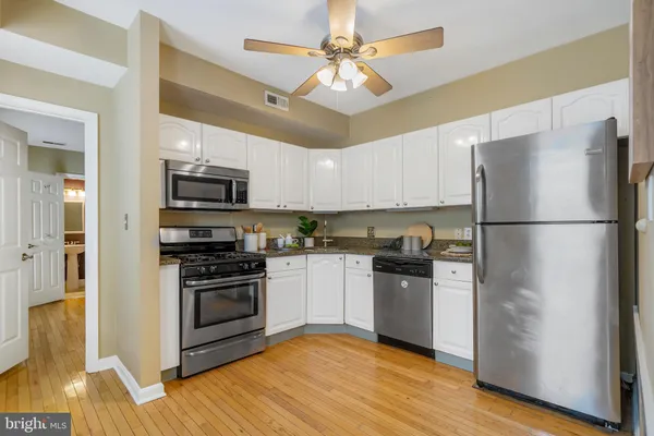 a kitchen with stainless steel appliances granite countertop a refrigerator stove a sink and dishwasher a oven with wooden floor