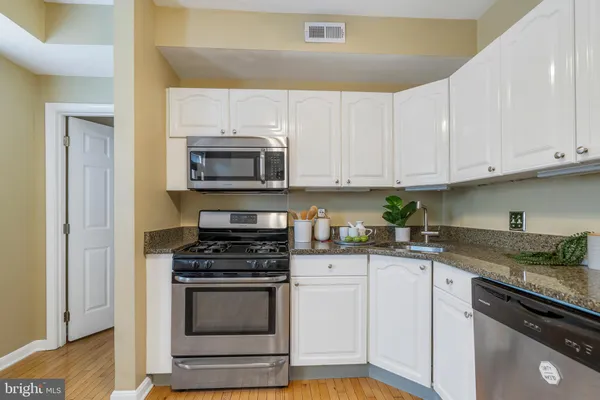 a kitchen with granite countertop white cabinets and stainless steel appliances