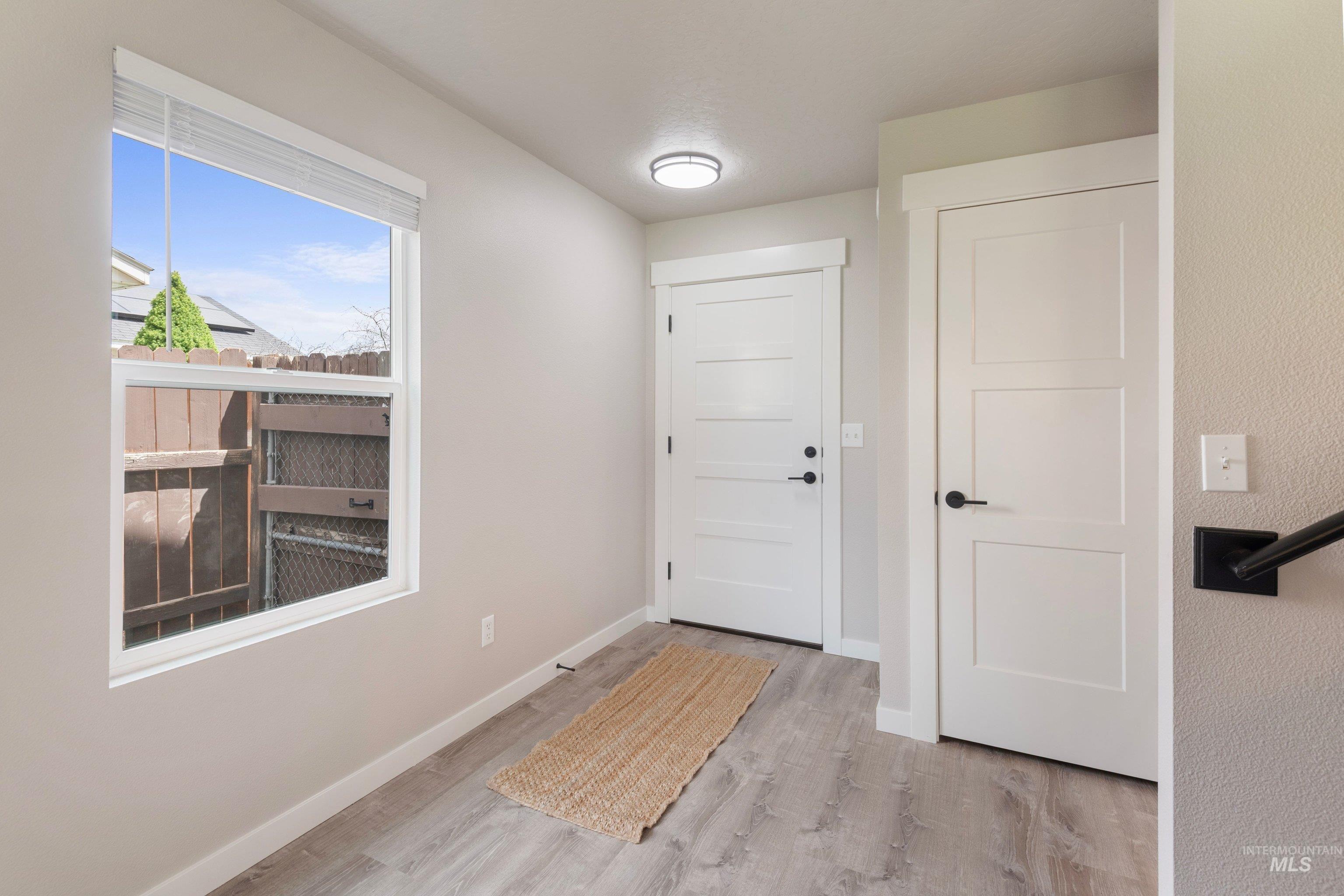 16759 Abram Avenue Caldwell, ID 83607 - Photo 6 of 33 Entryway featuring wood-finish flooring, a large window, and contemporary white doors with dark hardware