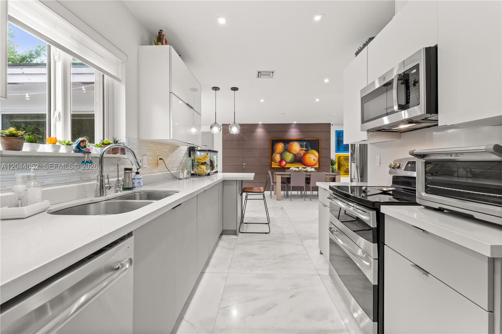 721 Bird Road Coral Gables, FL 33146 - Photo 9 of 24 a large kitchen with stainless steel appliances granite countertop a stove a sink and a microwave