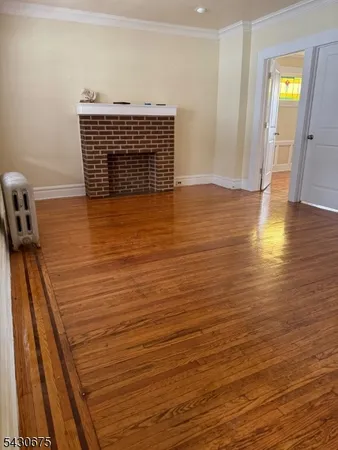 a view of empty room with window and wooden floor