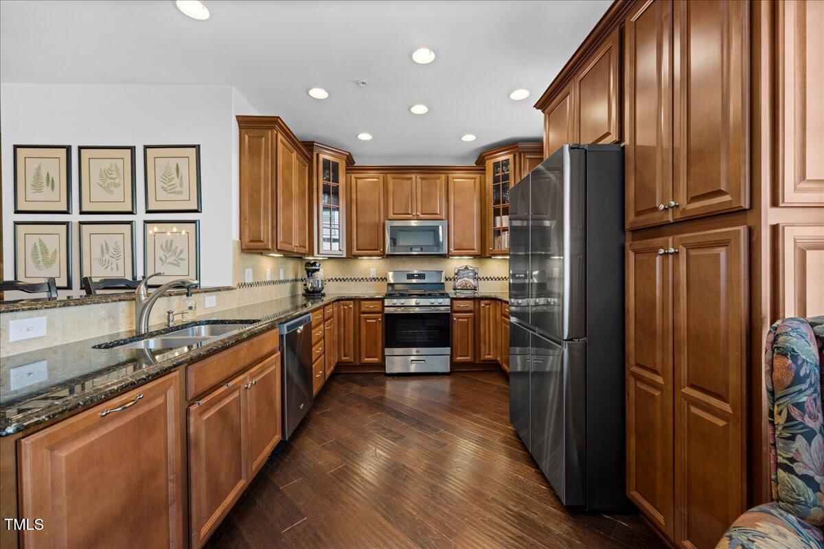 10520 Sablewood Drive, Unit 103 Raleigh, NC 27617 - Photo 10 of 38 a large kitchen with stainless steel appliances granite countertop a refrigerator a sink dishwasher a stove and a microwave oven with wooden floor