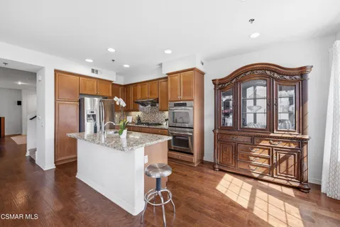 a living room with stainless steel appliances granite countertop furniture wooden floor and a view of kitchen
