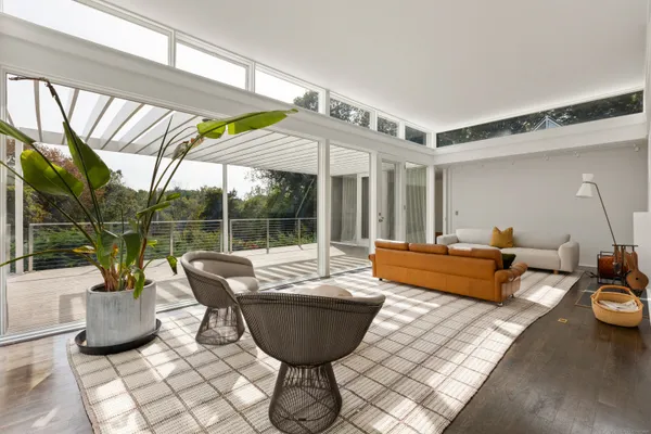 a living room with furniture floor to ceiling window and wooden floor