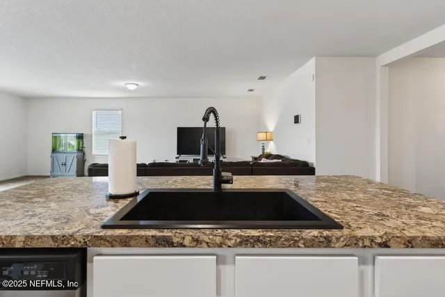 a kitchen with granite countertop a sink stove and refrigerator