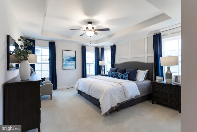 a spacious bedroom with a bed painting on wall and a flat tv screen