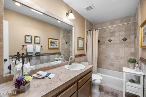 a bathroom with a granite countertop sink a toilet a mirror and shower
