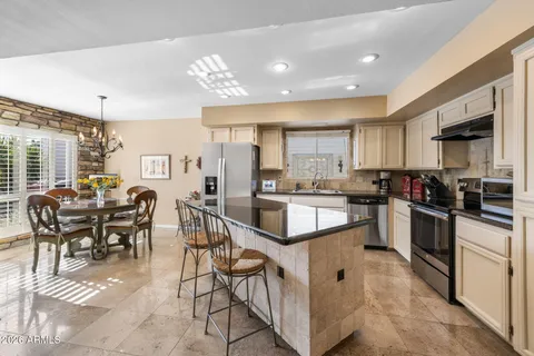 a kitchen with stainless steel appliances kitchen island granite countertop a stove a sink a refrigerator and white cabinets with wooden floor