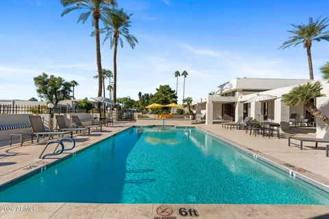 a view of a swimming pool with lawn chairs under an umbrella