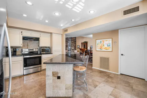 a kitchen with granite countertop a refrigerator and a stove top oven