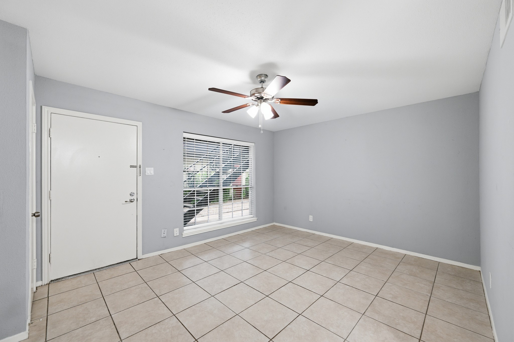 11550 Chimney Rock Road, Unit 133 Houston, TX 77035 - Photo 6 of 40 Bright and spacious room with neutral tile flooring, a ceiling fan, and a large window offering plenty of natural light.