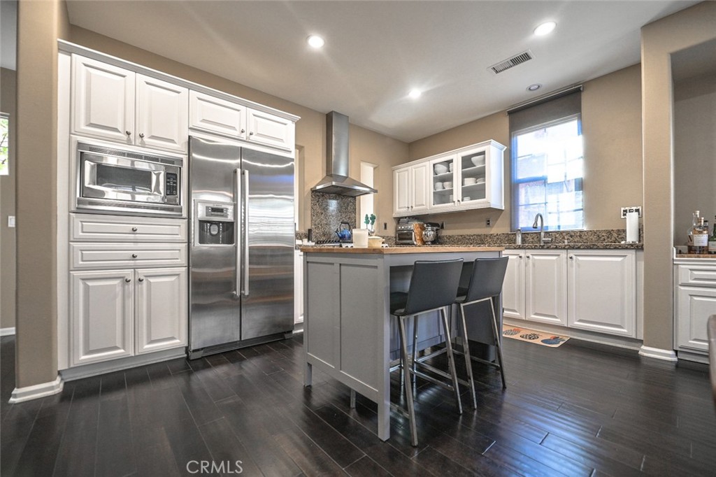 64 Scarlet Bloom Irvine, CA 92618 - Photo 9 of 22 a kitchen with stainless steel appliances granite countertop a table chairs refrigerator and sink