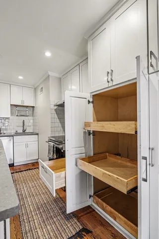 a kitchen with a refrigerator a stove and white cabinets with wooden floor