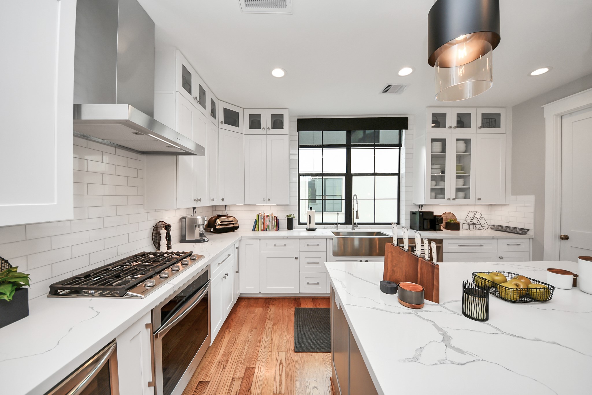 2765 Freund Street Houston, TX 77003 - Photo 15 of 44 This kitchen offers modern white cabinetry, stainless steel appliances, and a farmhouse sink. Featuring a spacious island, sleek gas stove, and abundant natural light, it's both inviting and functional.