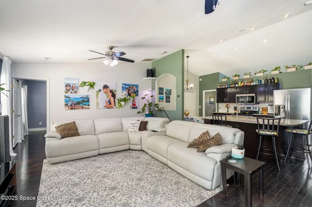 a living room with furniture kitchen view and a chandelier