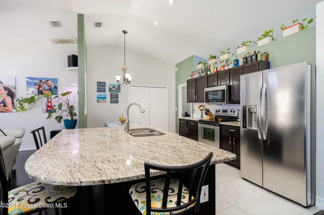a kitchen with stainless steel appliances granite countertop a sink dishwasher and refrigerator with wooden floor