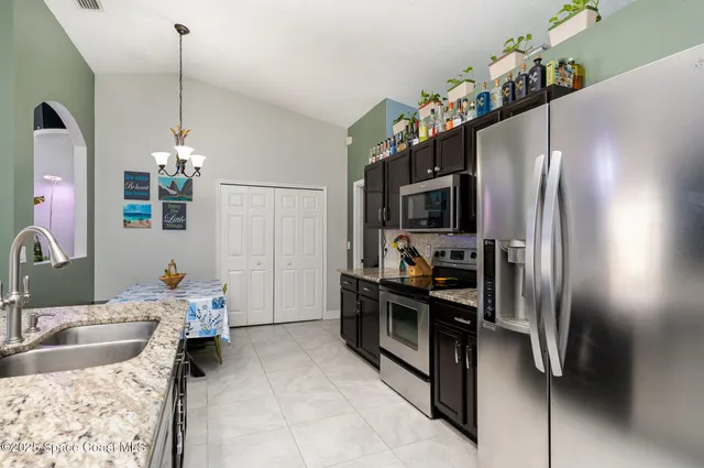 a kitchen with kitchen island granite countertop stainless steel appliances a sink stove and refrigerator