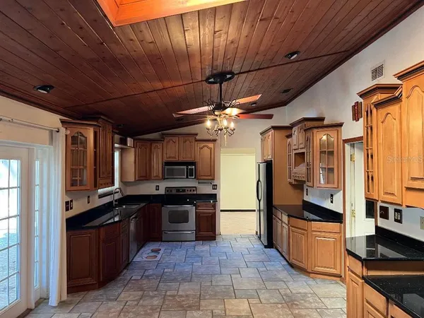 a large kitchen with stainless steel appliances wooden cabinets and a stove top oven