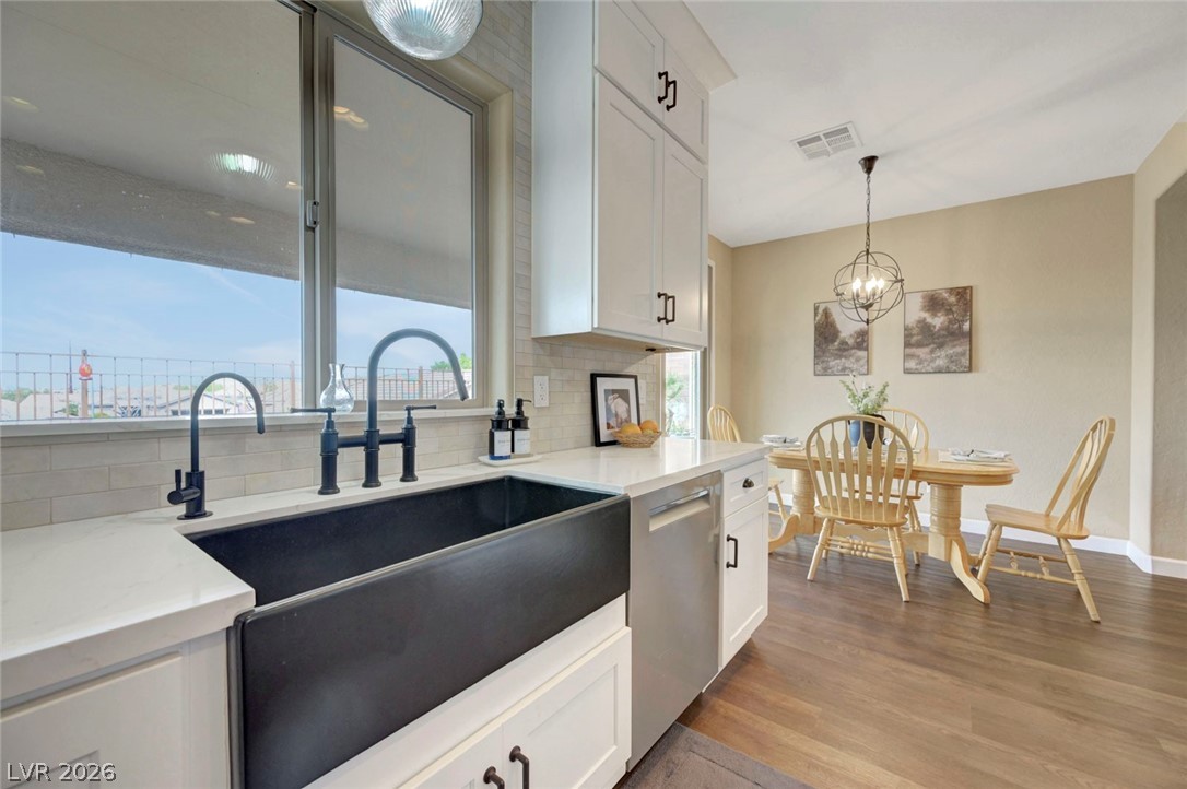 2700 Rue Montpellier Avenue Henderson, NV 89044 - Photo 18 of 39 Kitchen with white cabinets, decorative backsplash, light stone countertops, stainless steel dishwasher, and dark wood-type flooring