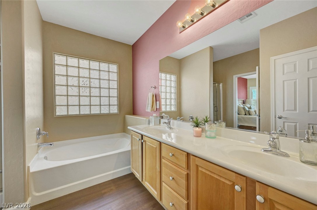 2700 Rue Montpellier Avenue Henderson, NV 89044 - Photo 25 of 39 Ensuite bathroom featuring double vanity, a garden tub, and dark wood-style flooring